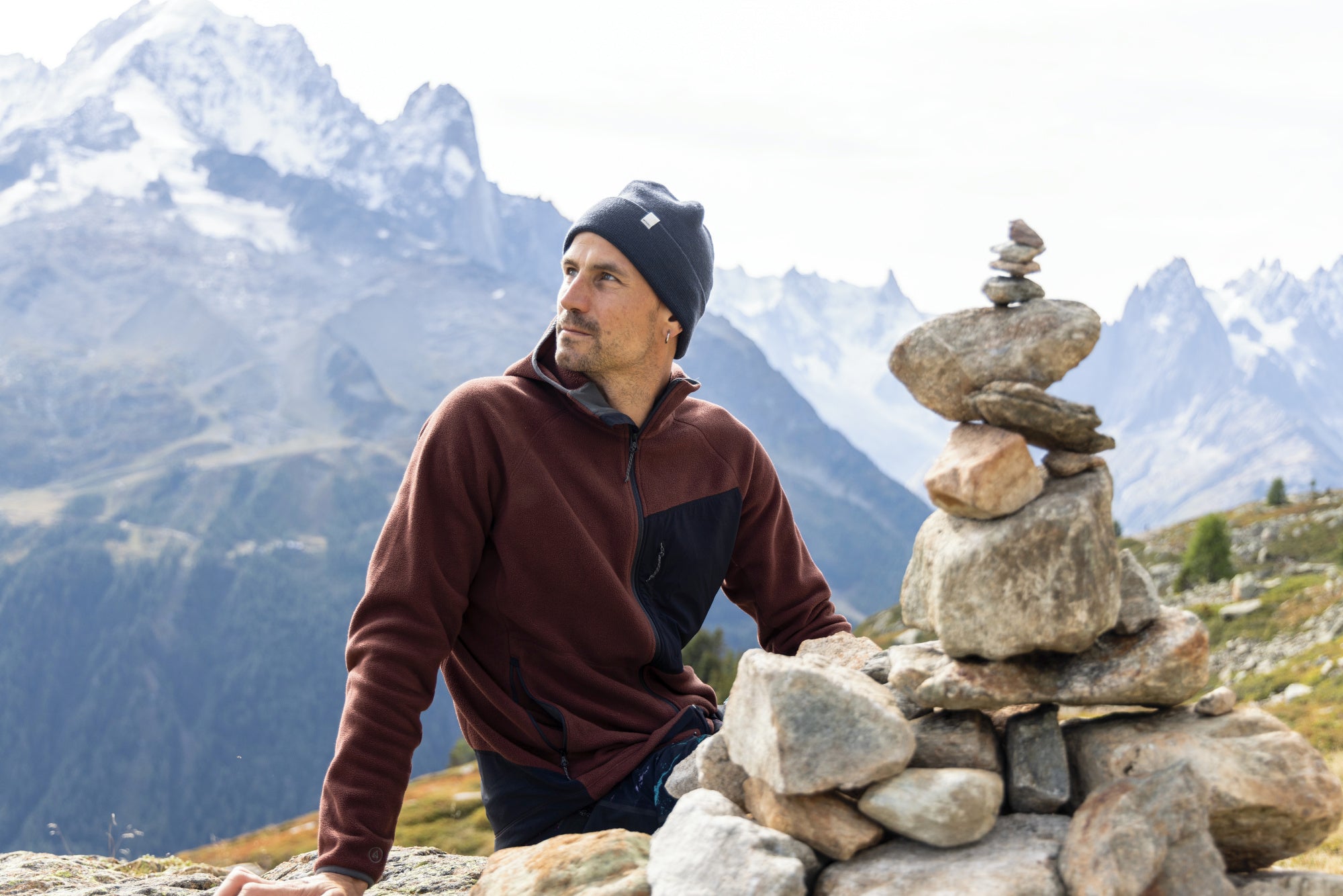 A man sitting on a rock wearing an ARTILECT midlayer fleece.